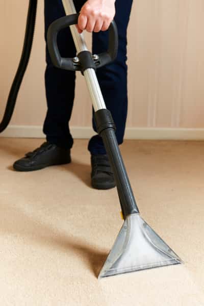 This is a photo of a man steam cleaning a cream carpet, using a professional steam cleaning machine works carried out by St St Paul's Cray Carpet Cleaning