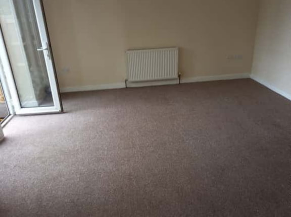 This is a photo of a living room after it has been cleaned. The room is empty and has a brown carpet that has been steam cleaned works carried out by St Paul's Cray Carpet Cleaning